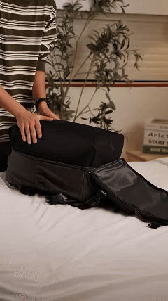 A traveler packing clothes inside the Atlas Travel Backpack